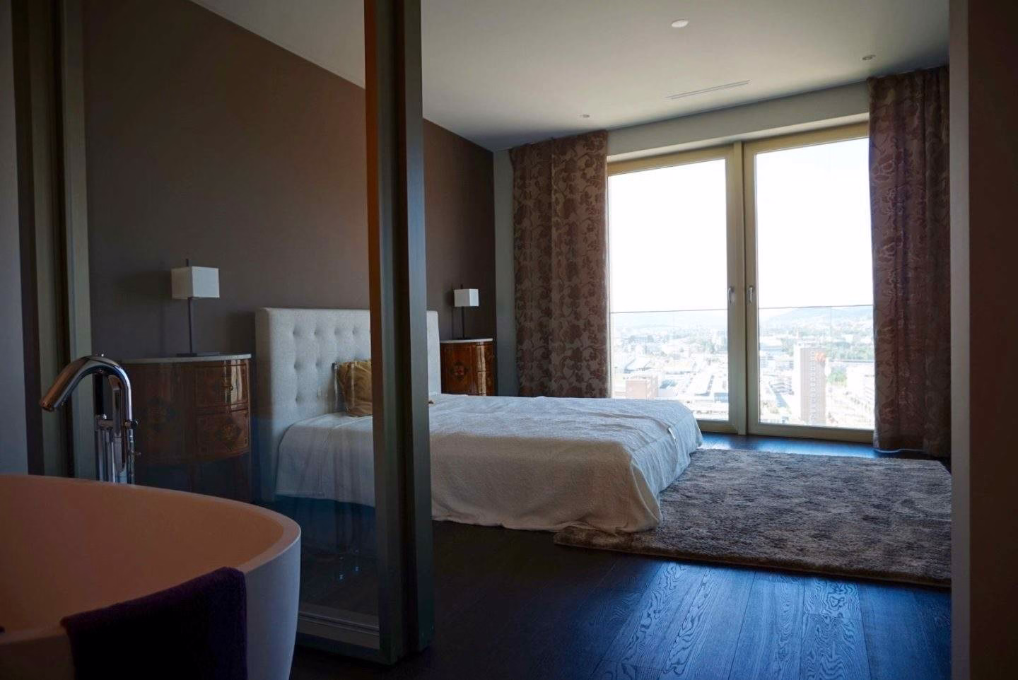 Schlafzimmer mit Akzentwand und offenem Badbereich im Mobimo Tower